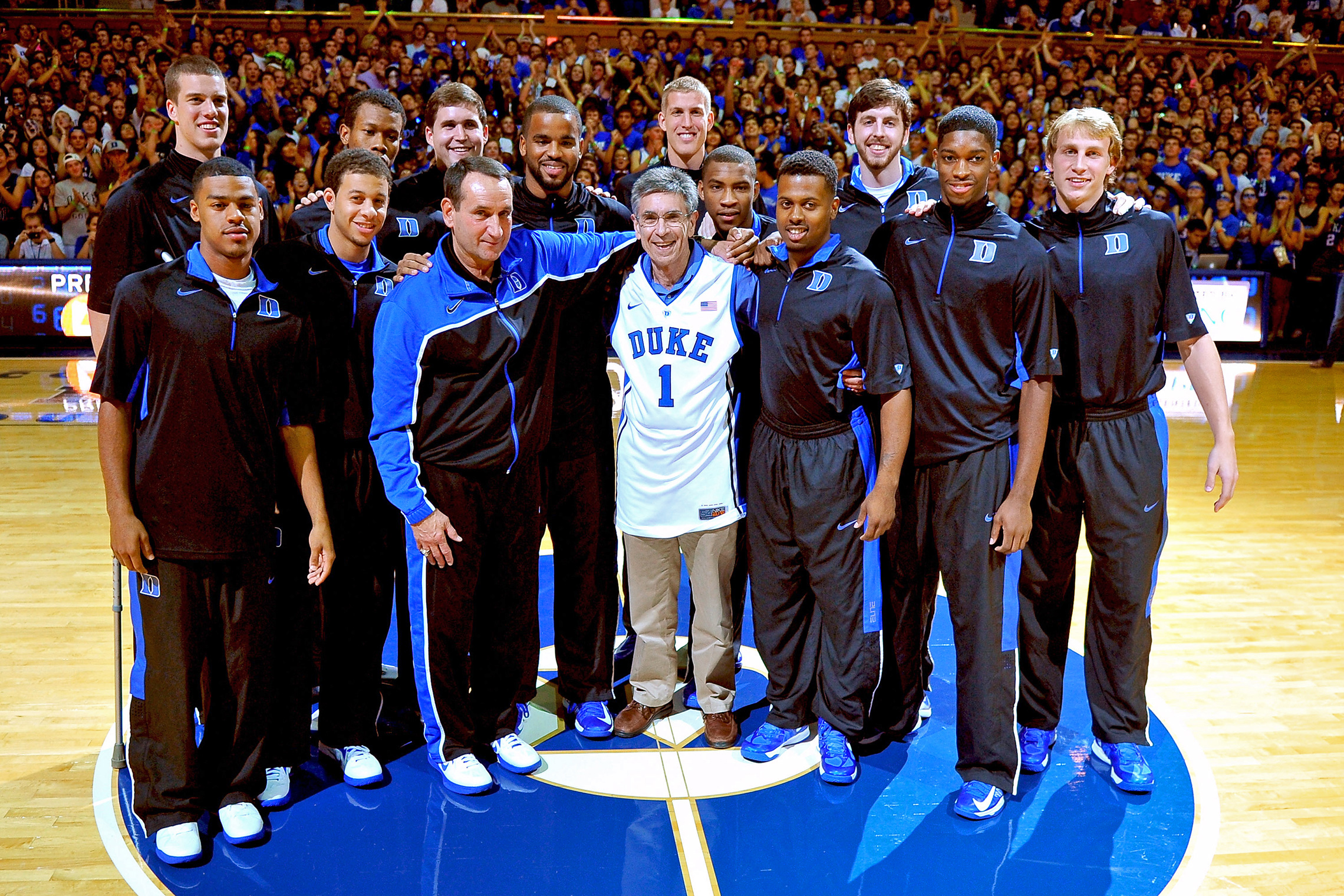 Head Coach Mike Krzyzewski (front, left) of the Duke Blue Devils and his team honor Dr. Robert Lefkowitz (center) during Countdown to Craziness at Duke University, after it was announced that Dr. Lefkowitz would receive the 2012 Nobel Prize in Chemistry. (Getty Images/ Lance King)