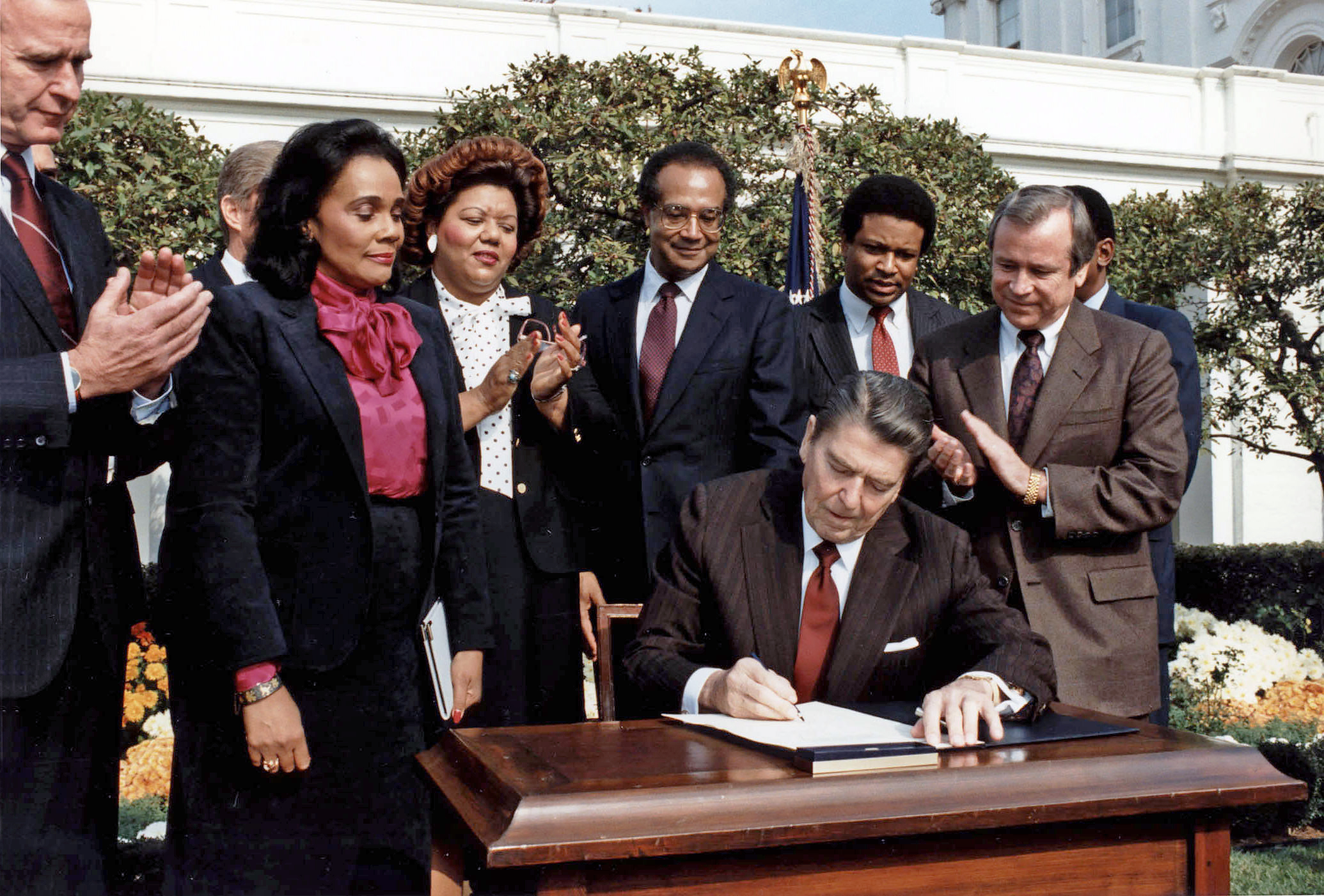 Coretta Scott King observa como el Presidente Ronald Reagan firma el proyecto de ley que conmemora el cumpleaños del Dr. Martin Luther King Jr. como fiesta nacional en noviembre. 2, 1983 en el Jardín de Rosas de la Casa Blanca. (Oficina Fotográfica de la Casa Blanca)'s birthday as a national holiday on Nov. 2, 1983 in the White House Rose Garden. (White House Photo Office)