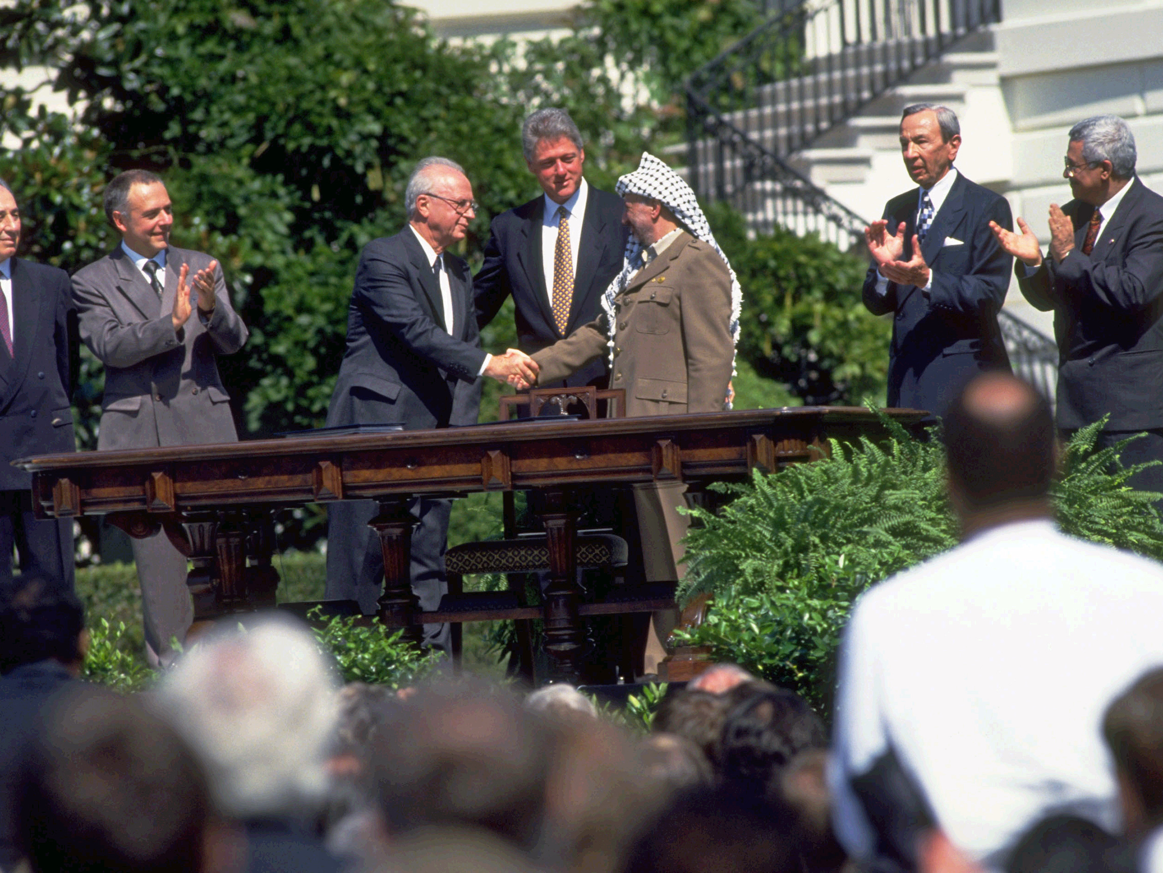 September 13, 1993: Prime Minister Yitzhak Rabin and Yasser Arafat shake hands after signing the peace accord between Israel and the Palestine Liberation Organization at the White House. President Bill Clinton stands behind them. Israeli Foreign Minister Shimon Peres looks on at left. (Richard T. Nowitz/CORBIS)